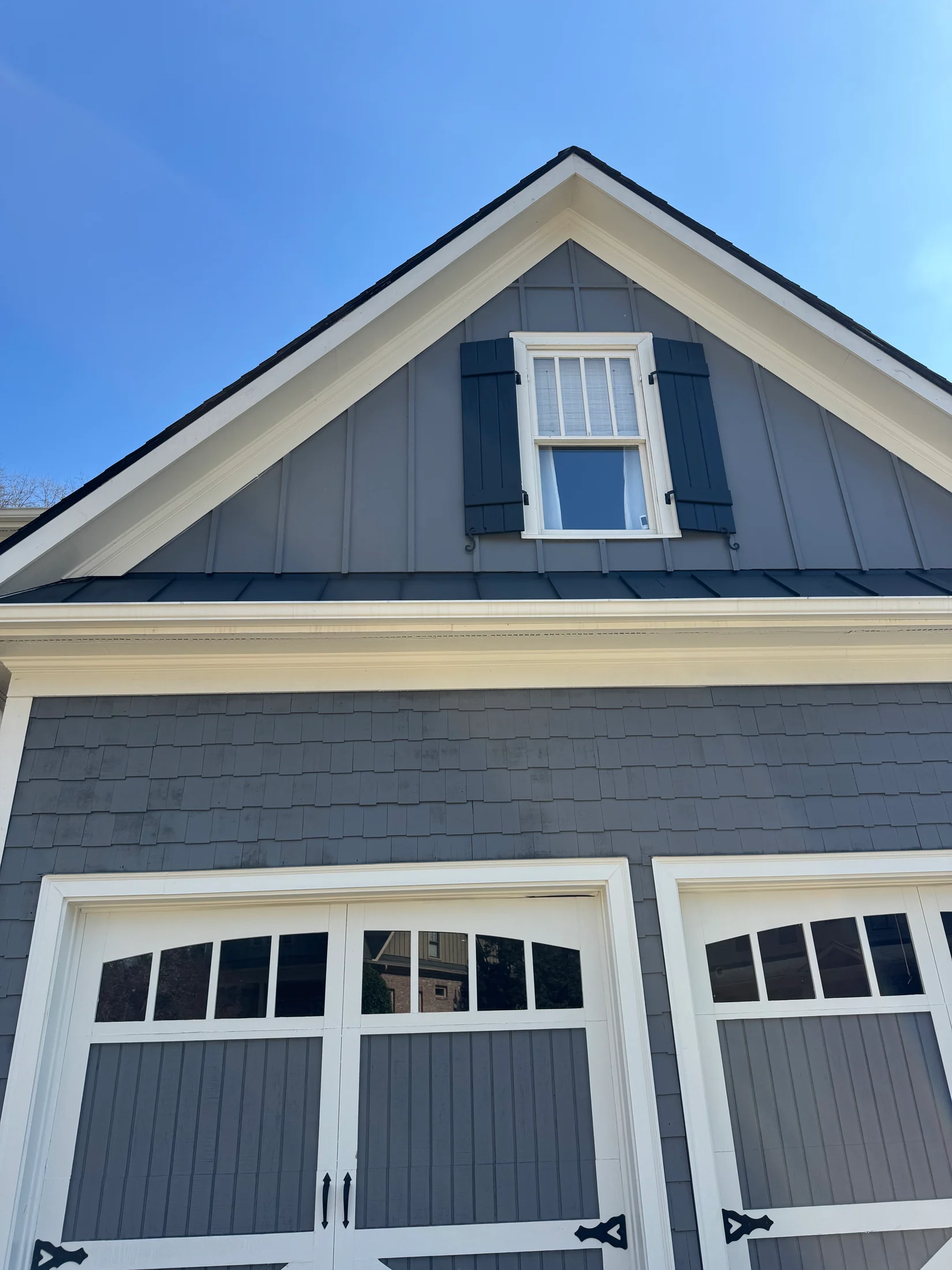 Summit field photo of a gray gable and garage doors framed by white trim and blue sky.